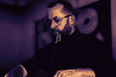 Un DJ en pleine performance, concentré sur ses platines dans une ambiance tamisée.