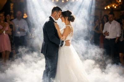 Un couple danse au milieu d'une piste entourée de fumée, éclairée par des projecteurs dans une ambiance festive.
