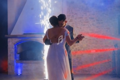 Un couple danse dans une ambiance festive avec des étincelles et des lumières colorées en arrière-plan.