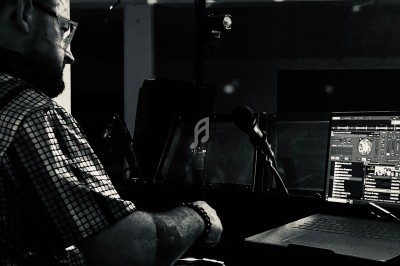 Un DJ mixant de la musique sur une table de mixage, avec un écran d'ordinateur affichant des pistes audio.