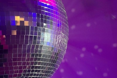 Boule à facettes argentée reflétant des lumières violettes et bleues dans une ambiance festive.