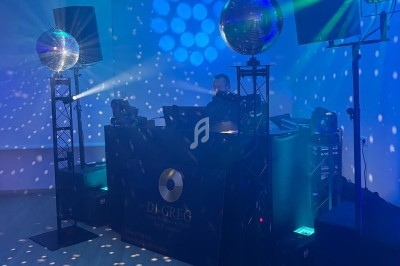 Deux tables de mixage avec DJ, entourées de lumières colorées et de boules à facettes dans une ambiance festive.