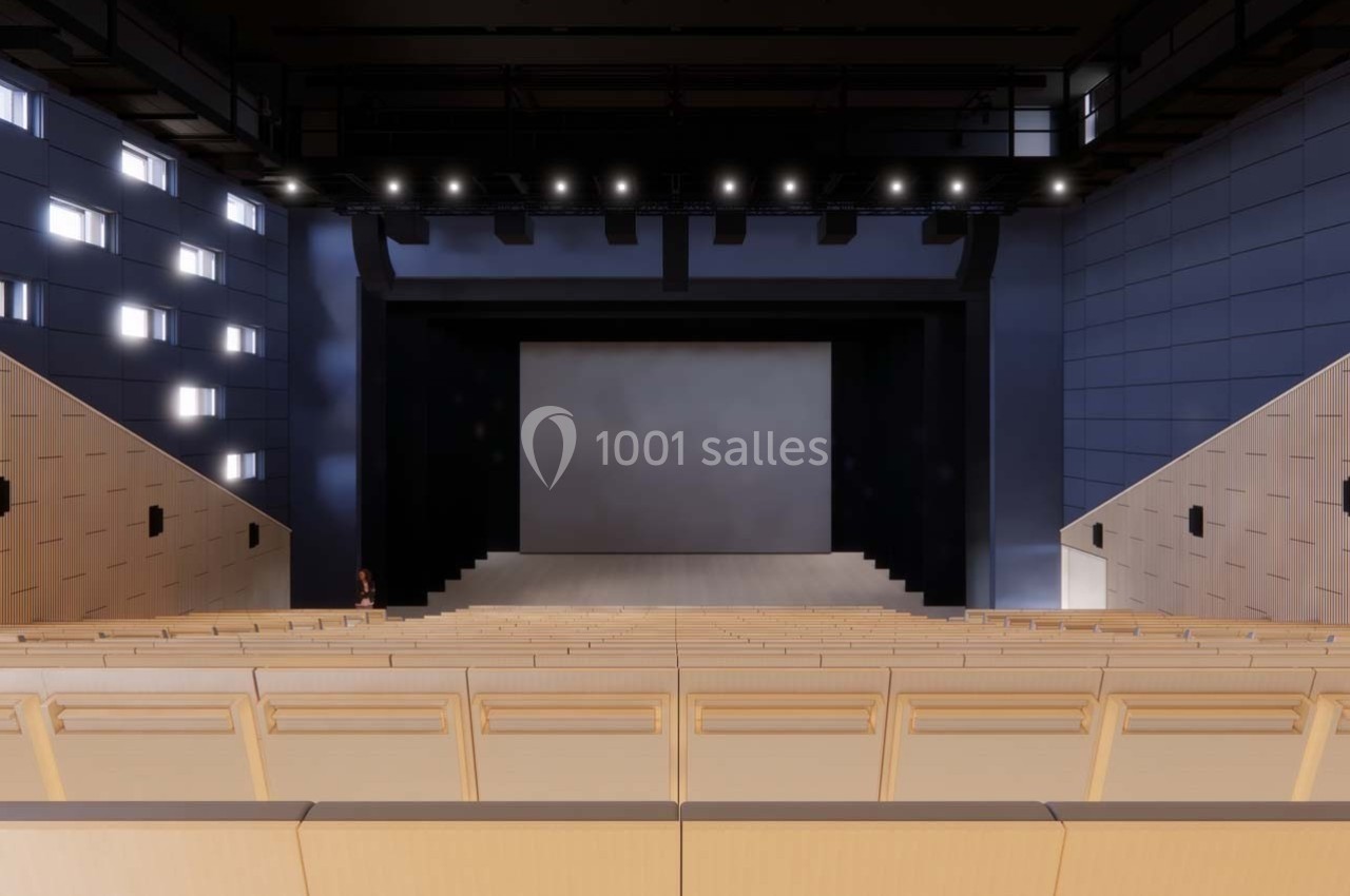 Vue intérieure d'un auditorium moderne avec des sièges en bois clair, une scène vide et un éclairage au plafond.