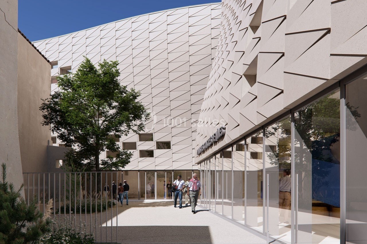 Façade moderne en relief d'un bâtiment avec des baies vitrées, une cour arborée et des personnes discutant.