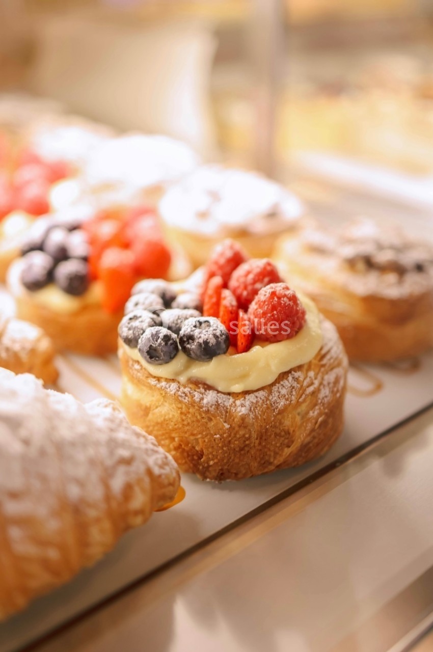 Pâtisseries feuilletées garnies de crème, framboises et myrtilles, présentées dans une vitrine.