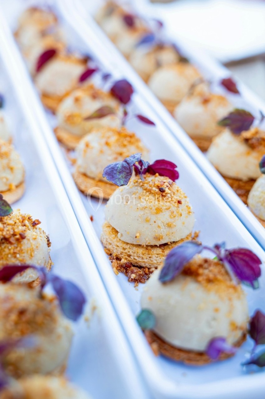 Bouchées apéritives élégantes sur un plateau, garnies de feuilles et d'éclats croustillants.