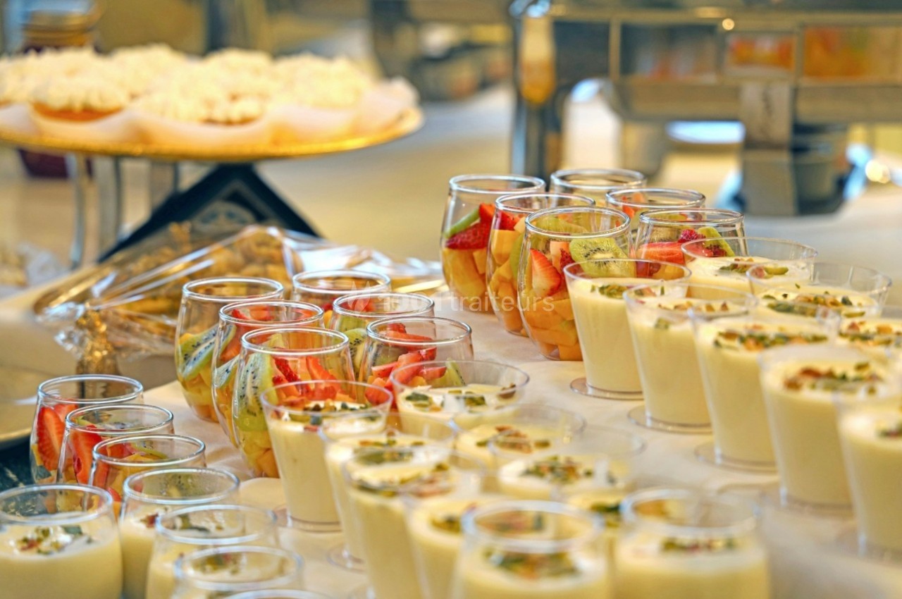 Desserts variés présentés dans des verrines, incluant des fruits frais et des crèmes, sur une table de buffet.
