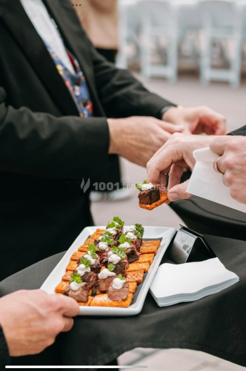 Des serveurs proposent des amuse-bouches sur un plateau lors d'un événement.
