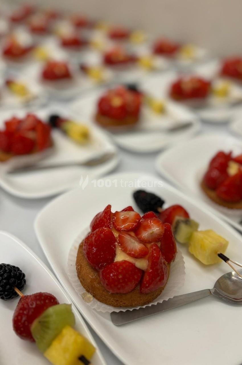Assortiment de tartelettes aux fruits frais, garnies de fraises, kiwis, mûres et ananas, servies sur des assiettes blanches.