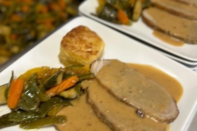 Assiette de burrata garnie de tomates cerises colorées et décorée d'une fleur violette sur une table blanche.
