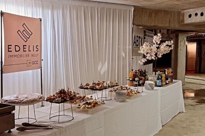 Assiette de burrata garnie de tomates cerises colorées et décorée d'une fleur violette sur une table blanche.