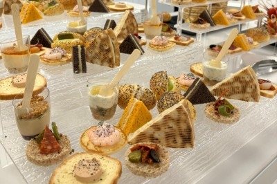 Assiette de burrata garnie de tomates cerises colorées et décorée d'une fleur violette sur une table blanche.