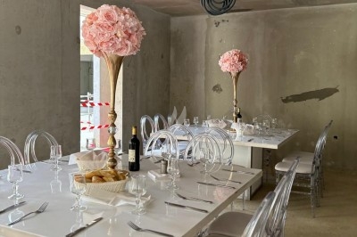 Assiette de burrata garnie de tomates cerises colorées et décorée d'une fleur violette sur une table blanche.