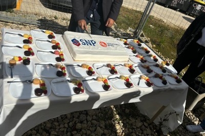 Assiette de burrata garnie de tomates cerises colorées et décorée d'une fleur violette sur une table blanche.