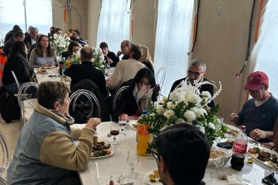 Assiette de burrata garnie de tomates cerises colorées et décorée d'une fleur violette sur une table blanche.