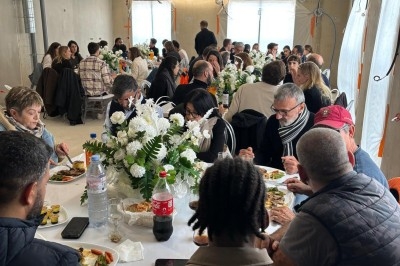 Assiette de burrata garnie de tomates cerises colorées et décorée d'une fleur violette sur une table blanche.