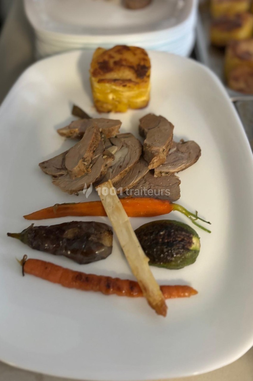 Assiette composée de tranches de viande, légumes grillés et gratin de pommes de terre, présentée sur un plat blanc.