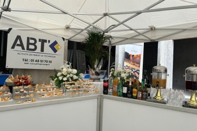 Assiette de burrata garnie de tomates cerises colorées et décorée d'une fleur violette sur une table blanche.