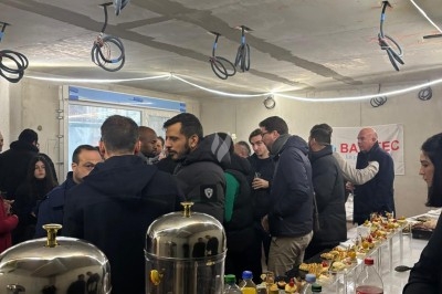 Assiette de burrata garnie de tomates cerises colorées et décorée d'une fleur violette sur une table blanche.