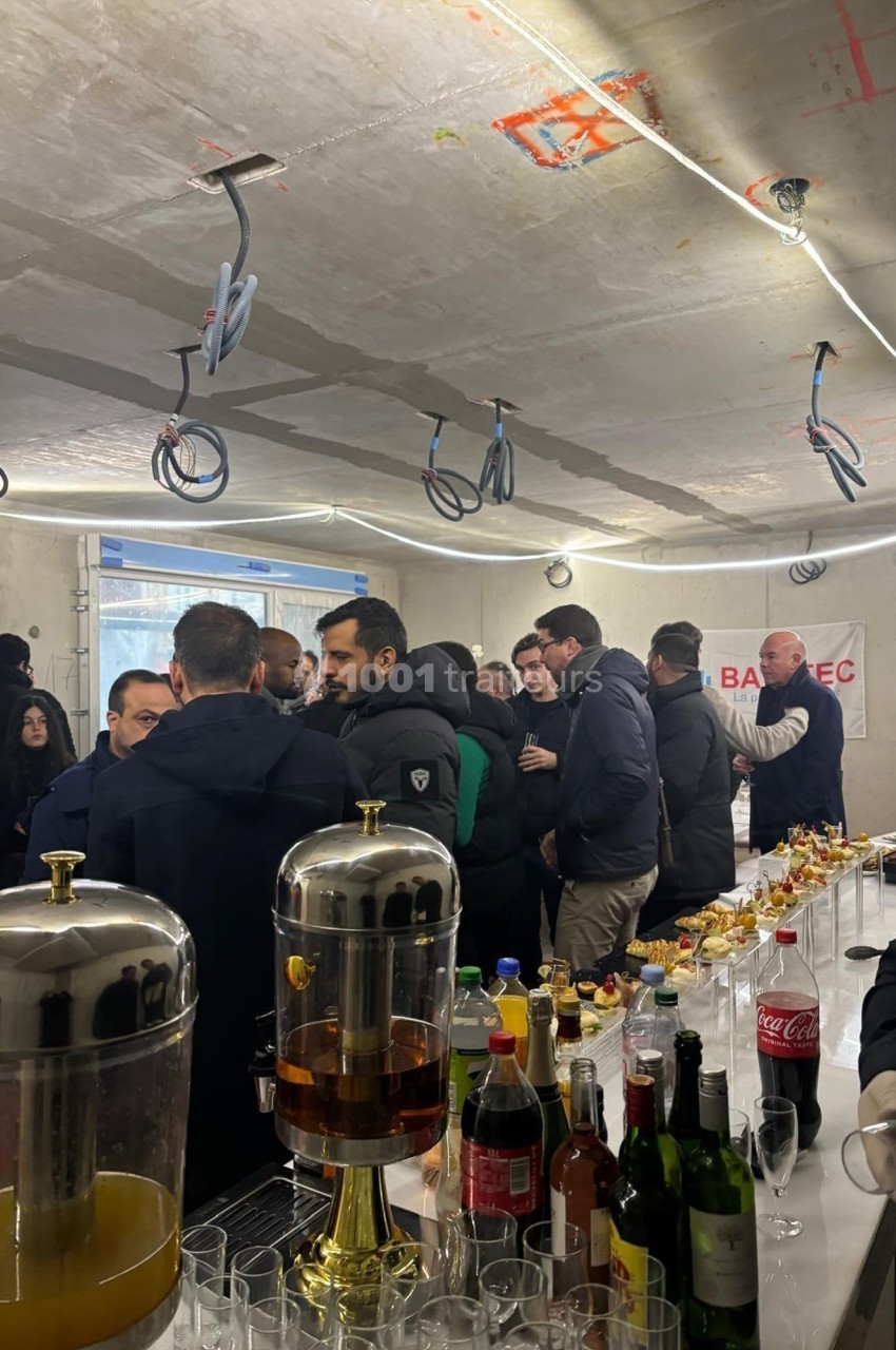 Des personnes rassemblées dans un espace en construction autour d'une table avec boissons et collations.