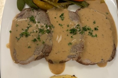 Assiette de burrata garnie de tomates cerises colorées et décorée d'une fleur violette sur une table blanche.