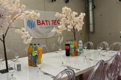 Assiette de burrata garnie de tomates cerises colorées et décorée d'une fleur violette sur une table blanche.