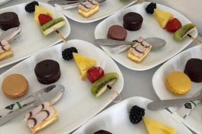 Assiette de burrata garnie de tomates cerises colorées et décorée d'une fleur violette sur une table blanche.