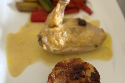 Assiette de burrata garnie de tomates cerises colorées et décorée d'une fleur violette sur une table blanche.