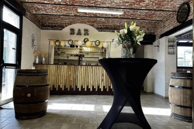 Miniature Location salle Maretz (Nord) - California #16 Salle avec un bar en bois, décorée de briques apparentes, tonneaux et une table haute ornée de fleurs blanches.