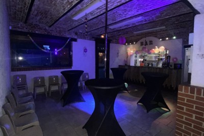 Miniature Location salle Maretz (Nord) - California #11 Salle avec un bar en bois, décorée de briques apparentes, tonneaux et une table haute ornée de fleurs blanches.