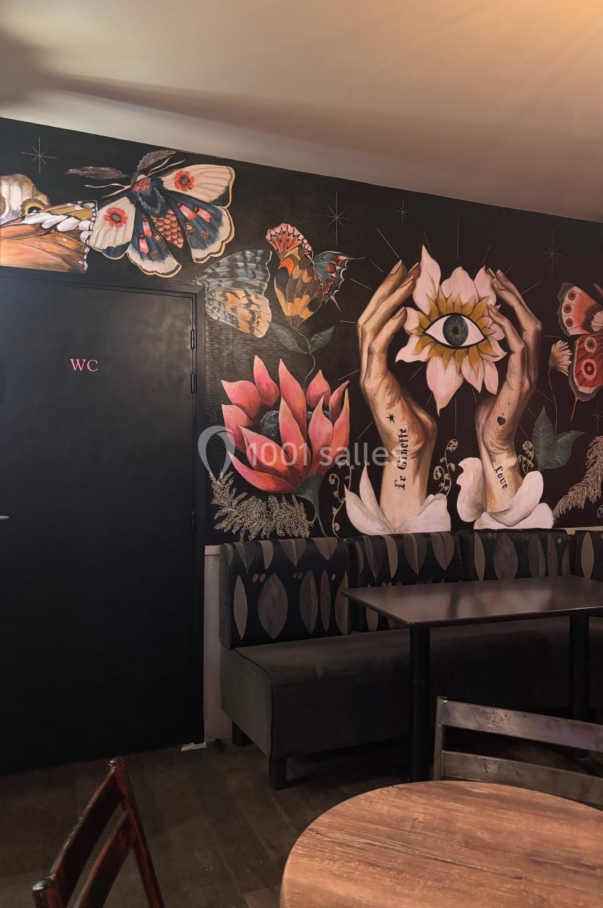 Peinture murale colorée représentant des mains tenant une fleur avec un œil, entourée de papillons et de motifs floraux.