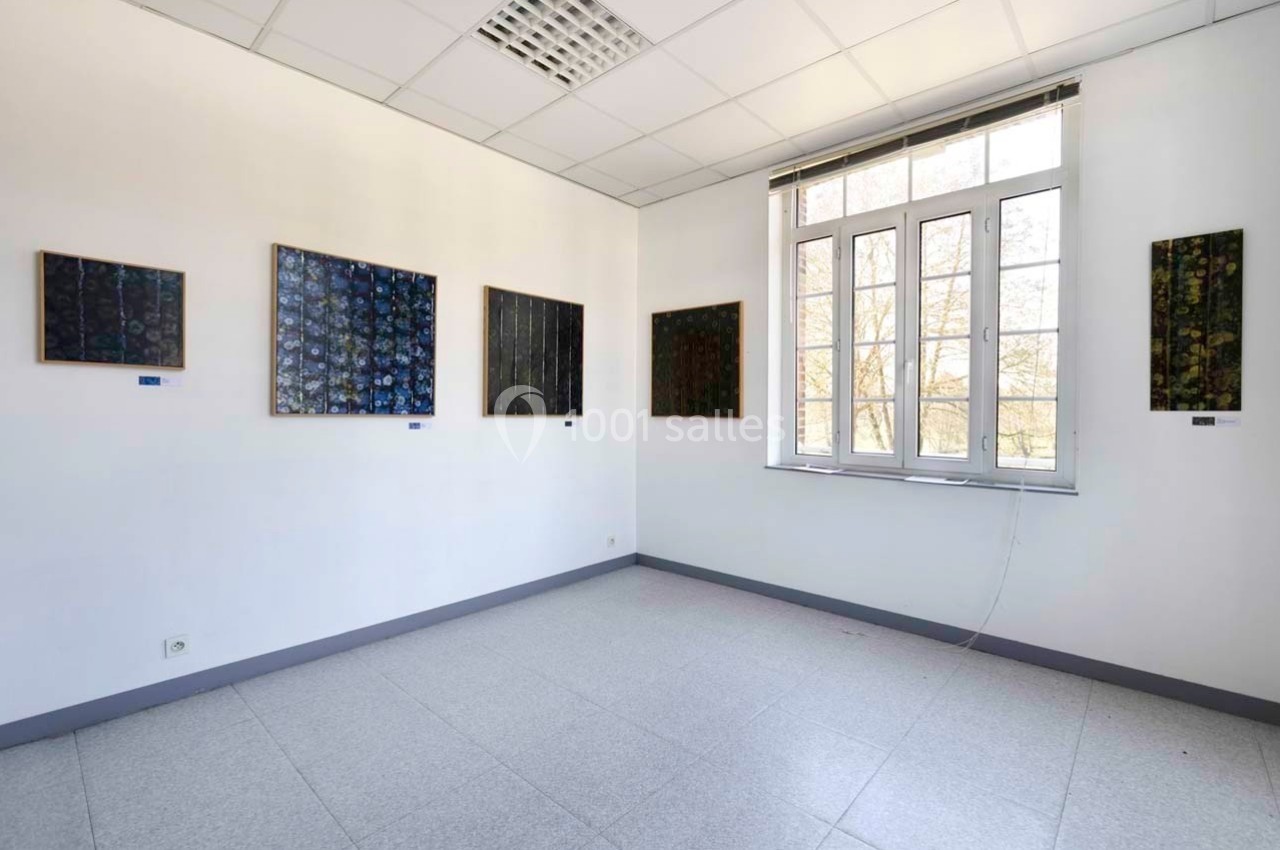 Salle d'exposition lumineuse avec plusieurs tableaux abstraits accrochés sur des murs blancs.