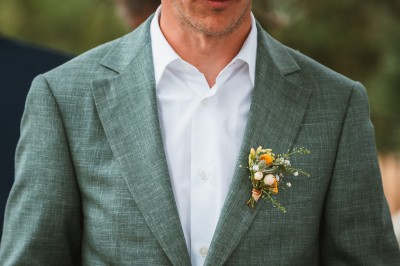 Miniature John Croizé Photographie #8 Un couple en tenue de mariage, l'homme portant la femme dans ses bras devant un mur en pierre ancienne.