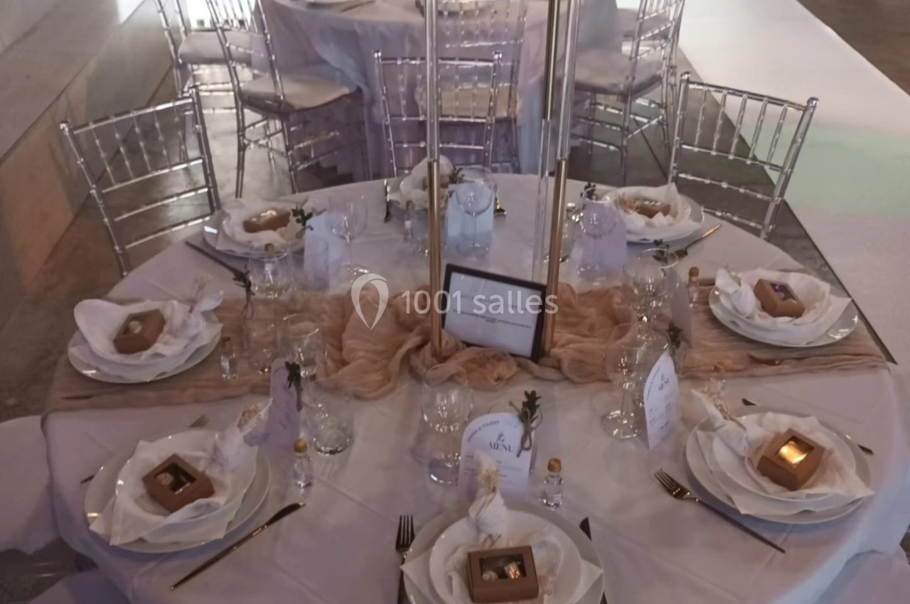 Table de réception élégamment dressée avec vaisselle blanche, décorations florales et cadeaux pour les invités.