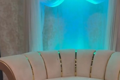 Salle de réception élégante avec tables rondes dressées, chaises transparentes et décorations florales sur chandeliers dorés.