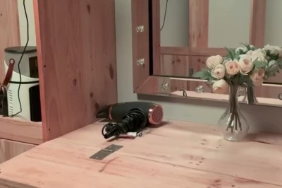 Salle de réception élégante avec tables rondes dressées, chaises transparentes et décorations florales sur chandeliers dorés.