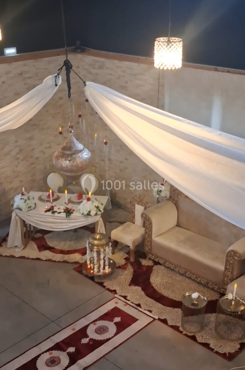 Décoration intérieure avec un canapé, une table ornée de bougies et de fleurs, et des voilages suspendus.