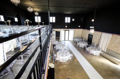 Coiffeuse en bois avec miroir éclairé, chaise grise et mur en pierre décorative en arrière-plan.