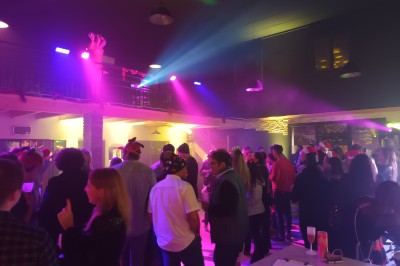 Coiffeuse en bois avec miroir éclairé, chaise grise et mur en pierre décorative en arrière-plan.