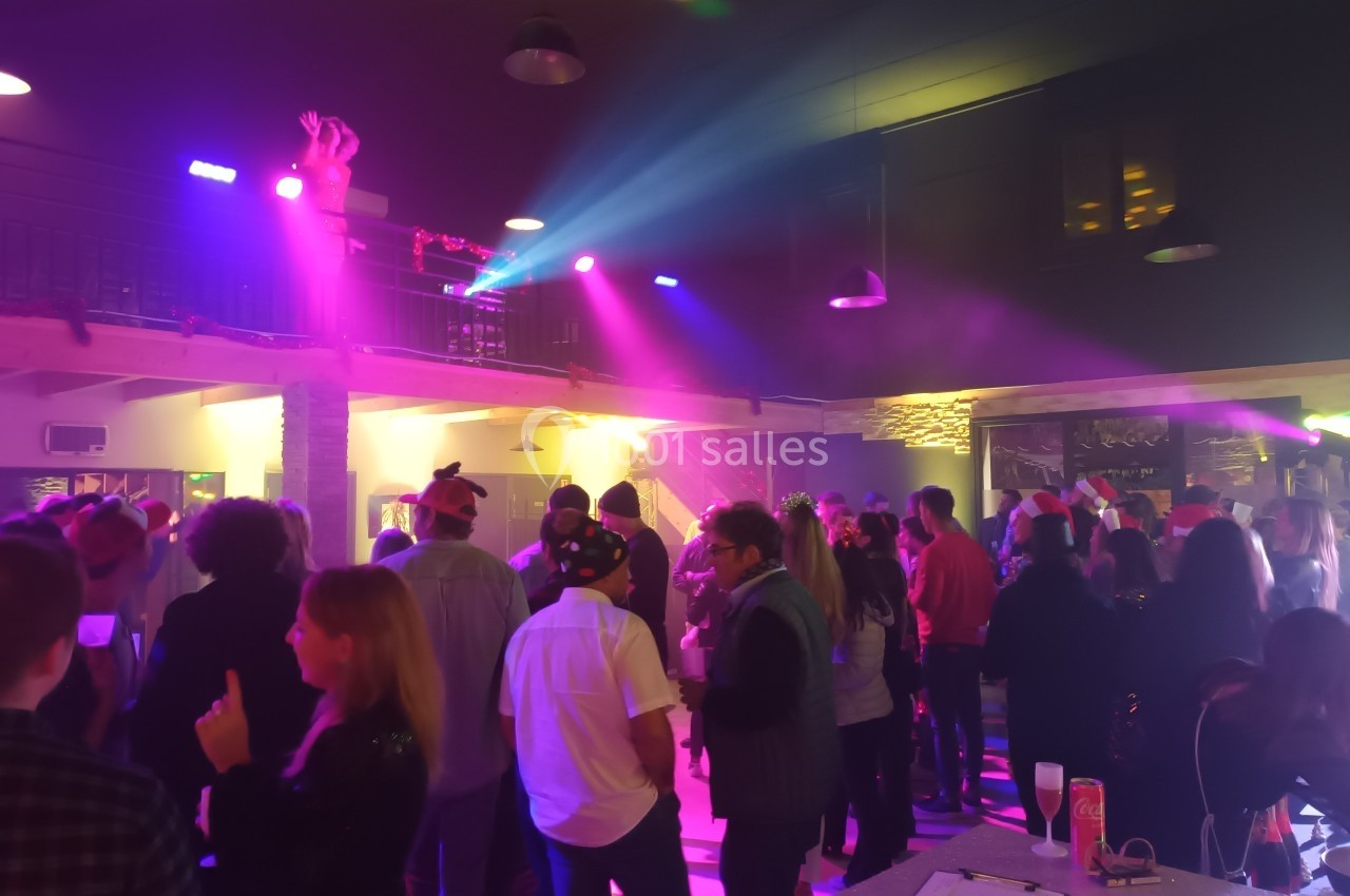 Groupe de personnes dans une salle éclairée par des lumières colorées lors d'un événement festif en intérieur.