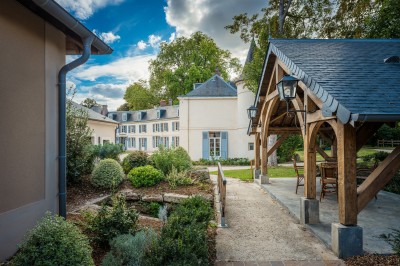Salle de bain moderne avec lavabo sur plan en bois, miroir éclairé et douche à paroi en marbre noir.