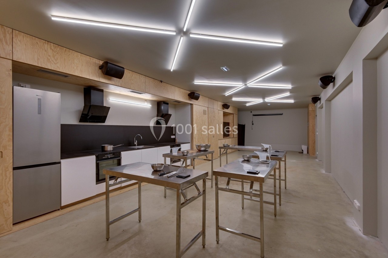 Cuisine moderne avec plans de travail en acier inoxydable, éclairage au plafond et équipements intégrés.