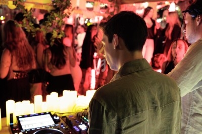 Un DJ mixe de la musique sur une console dans une ambiance festive et éclairée par des bougies.