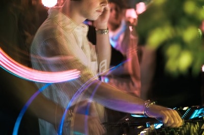 Un DJ mixe de la musique en soirée, entouré de lumières colorées et d'effets lumineux.