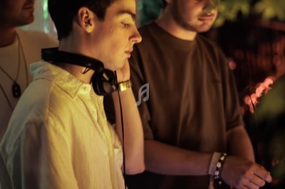 Trois DJ mixant de la musique dans une ambiance nocturne avec des lumières tamisées et des décorations suspendues.