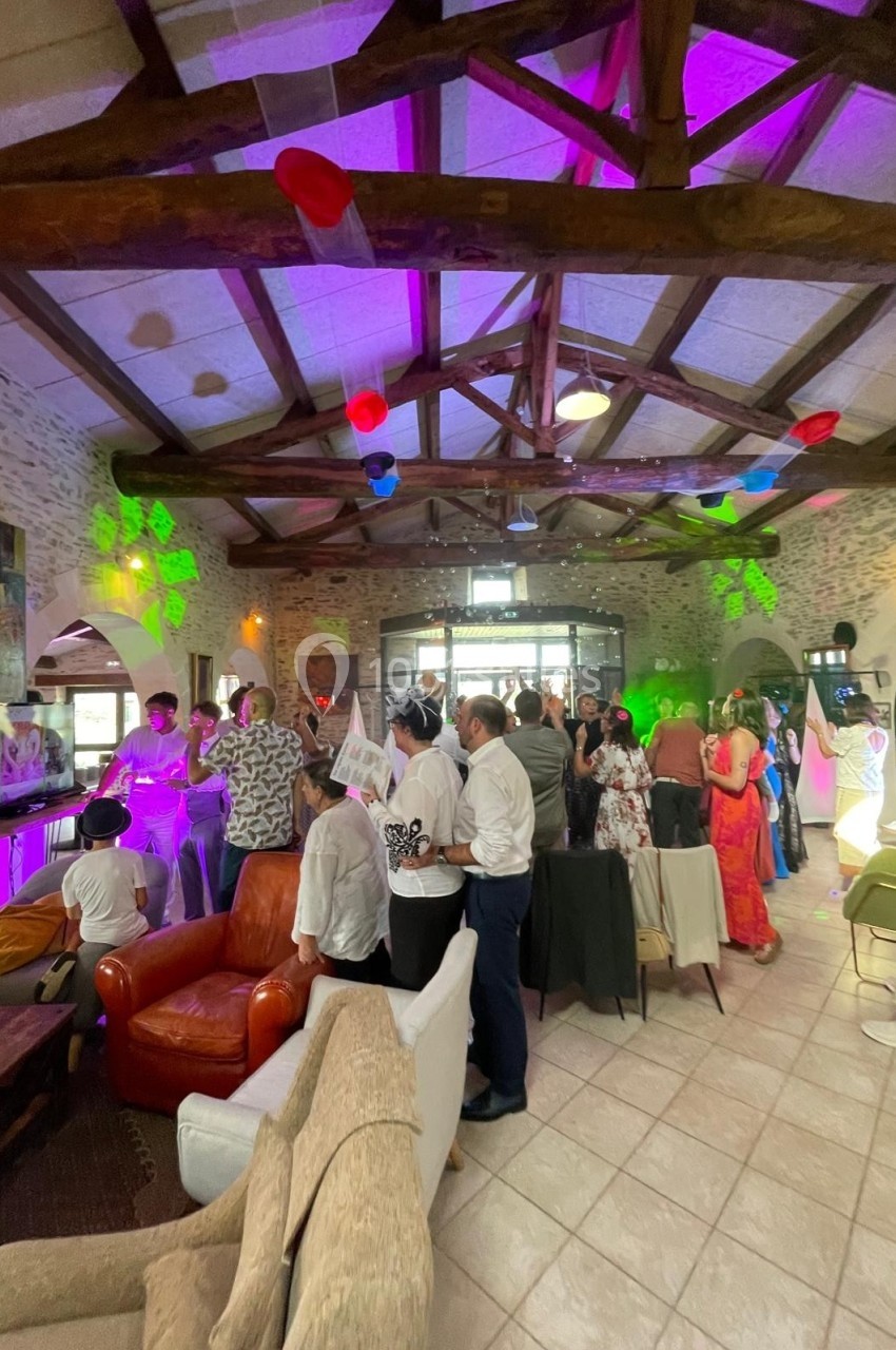 Groupe de personnes debout dans une salle décorée, éclairée par des lumières colorées, lors d'un événement festif.