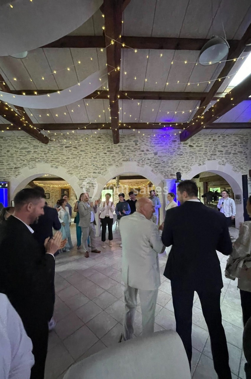 Groupe de personnes debout dans une salle en pierre avec des lumières suspendues au plafond.