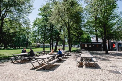 Façade d'un bâtiment commercial avec enseigne ’Comera Cuisines’ et affiches publicitaires, entouré de végétation.