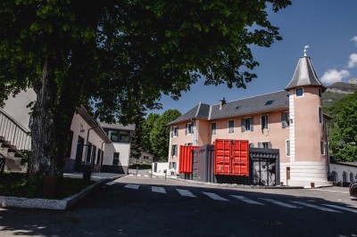 Façade d'un bâtiment commercial avec enseigne ’Comera Cuisines’ et affiches publicitaires, entouré de végétation.