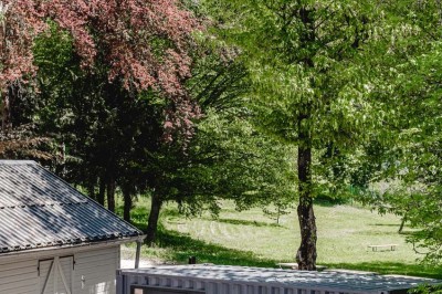 Façade d'un bâtiment commercial avec enseigne ’Comera Cuisines’ et affiches publicitaires, entouré de végétation.